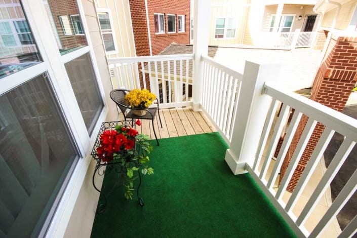 balcony view with green turf, a chair, and plants at Commons at Little Bark Creek Affordable Apartments in Fremont, Oh